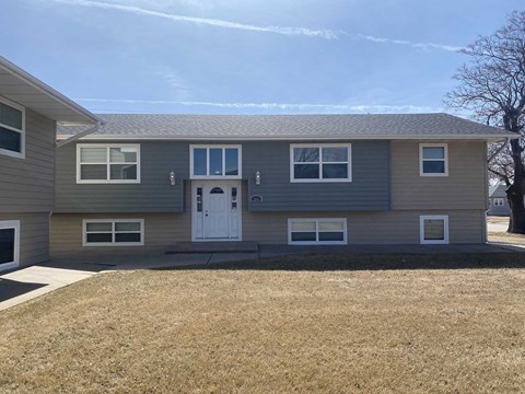 a gray house with a white door and a yard