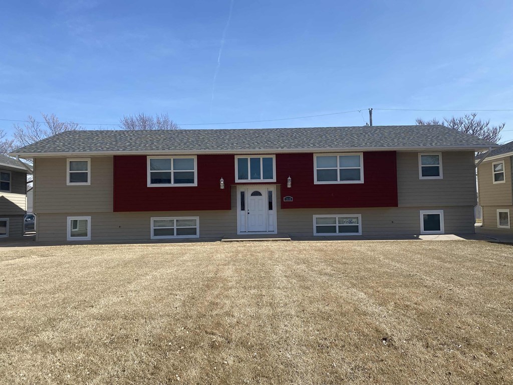 a red and tan house with a yard in front of it