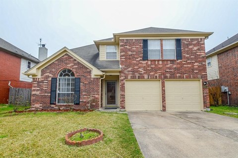 a brick house with two garage doors and a driveway