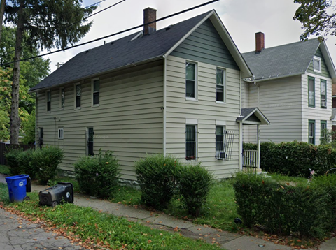 A house with a grey siding and a dark roof with a chimney.