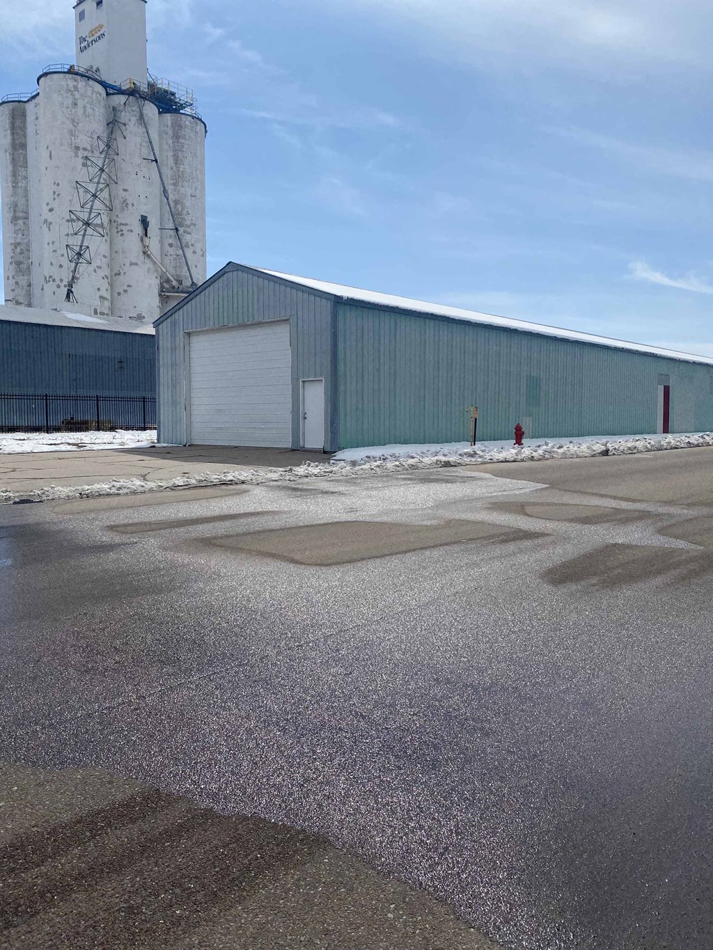 a large industrial building with a silo and a parking lot