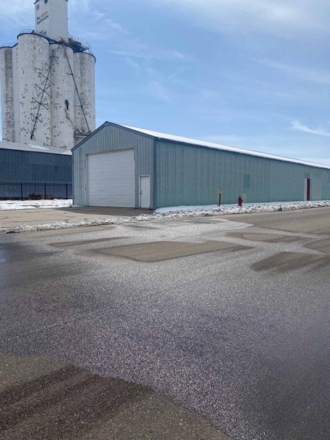 a large industrial building with a silo and a parking lot