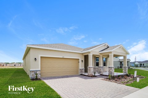 A house with a garage door and a brick pathway leading to it.
