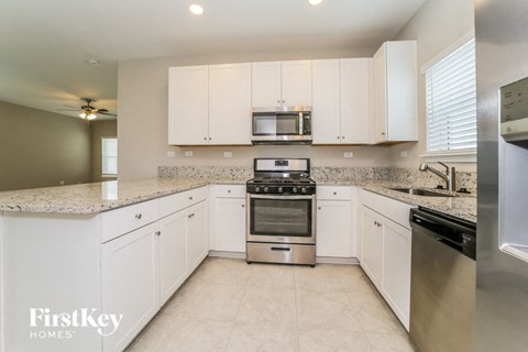 a kitchen with white cabinets and granite counter tops and stainless steel appliances