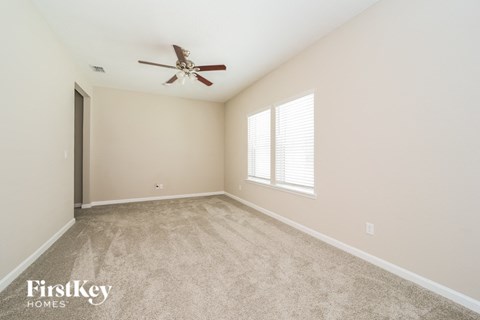 a spacious living room with carpet and a ceiling fan