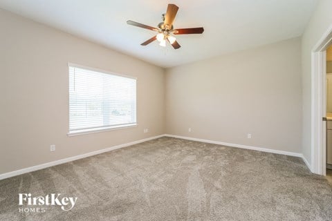the master bedroom has a carpeted floor and a ceiling fan