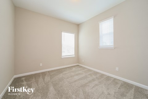 a spacious room with carpet and two windows