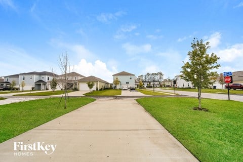 a suburban street with houses and green grass and a sidewalk