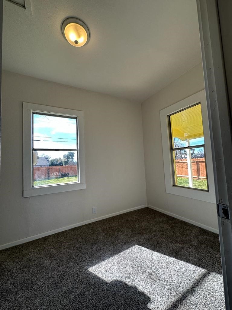 an empty room with carpet and two windows