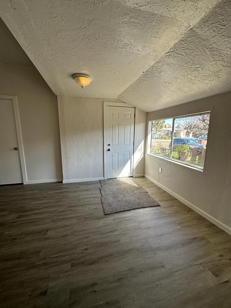 an empty living room with a large window and wooden floors