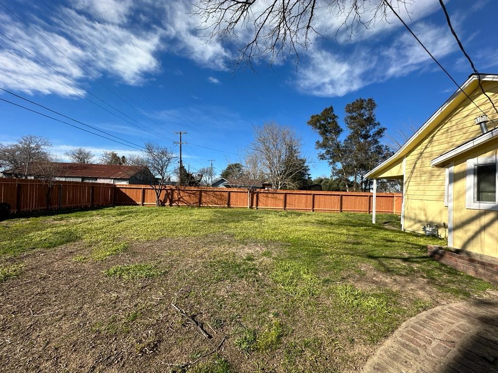 a backyard with a fence and a yellow house
