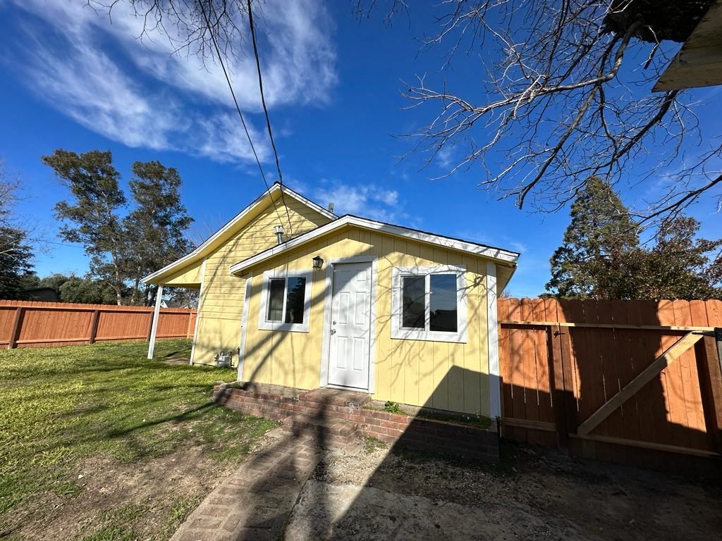 a small yellow house next to a wooden fence