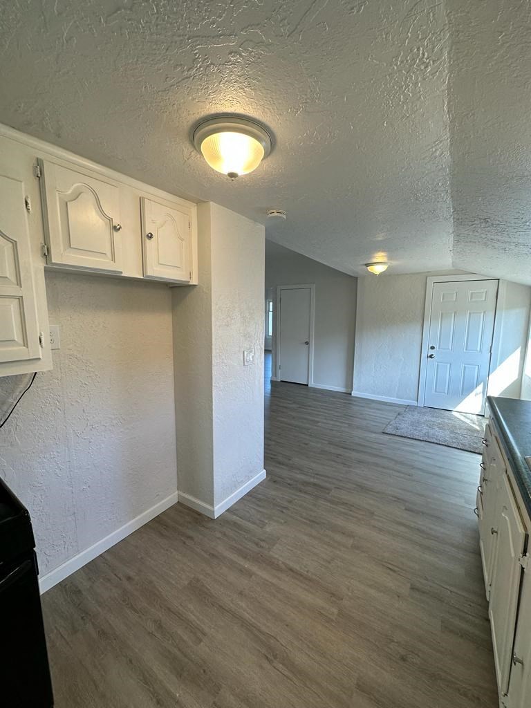 an empty kitchen and hallway with white cabinets