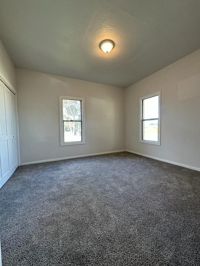 an empty living room with carpet and a window