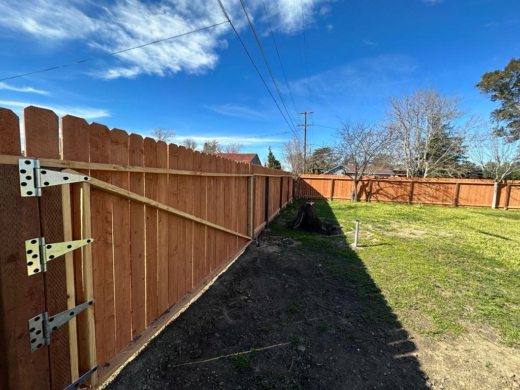 a wooden fence in a yard with a blue sky