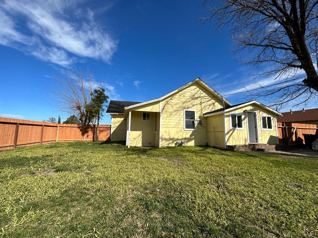 a yellow house with a yard and a fence