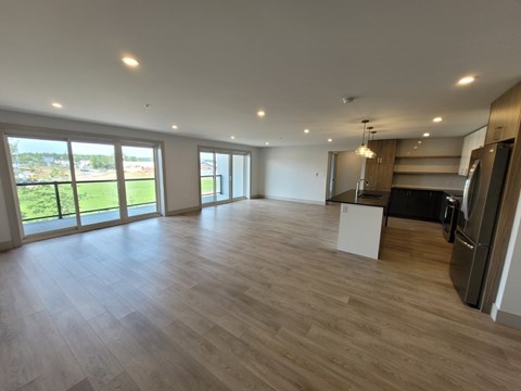 A spacious room with wooden flooring and large windows.
