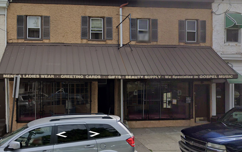 A car is parked in front of a store that specializes in gospel music.