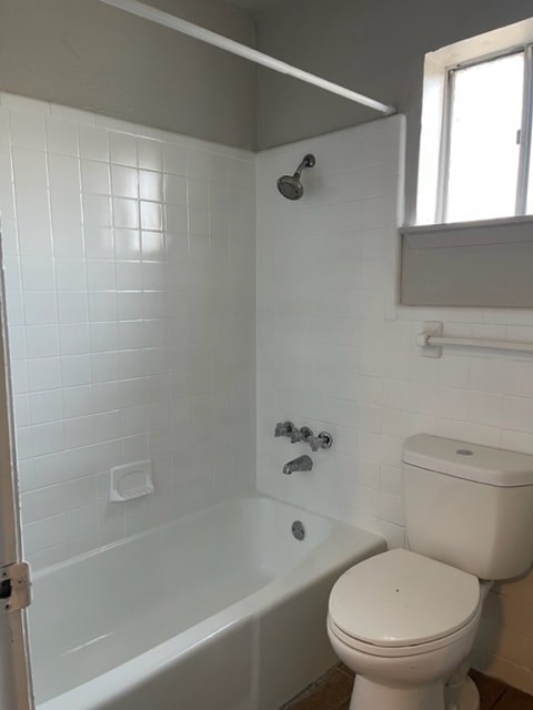 A white toilet sits next to a bathtub in a bathroom.