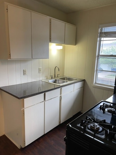 A kitchen with white cabinets and a black stove top.