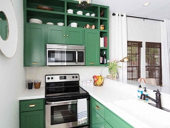 a kitchen with green cabinets and a stove and a microwave