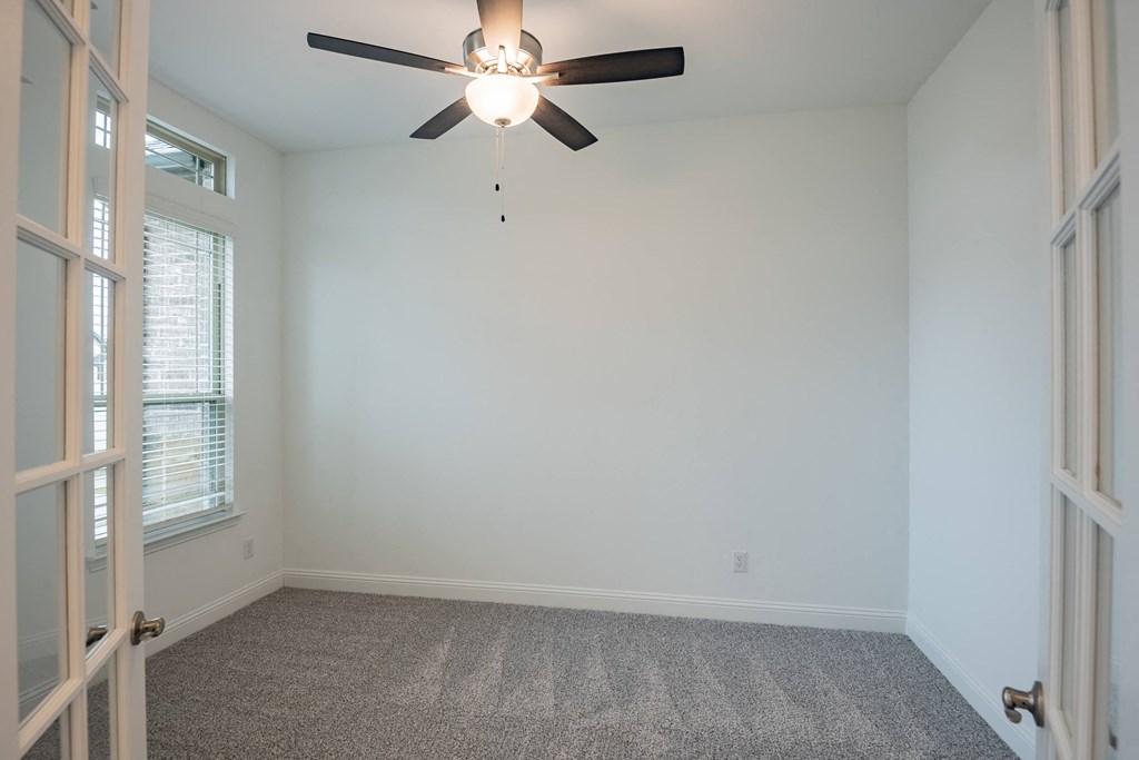 an empty room with a ceiling fan and a window