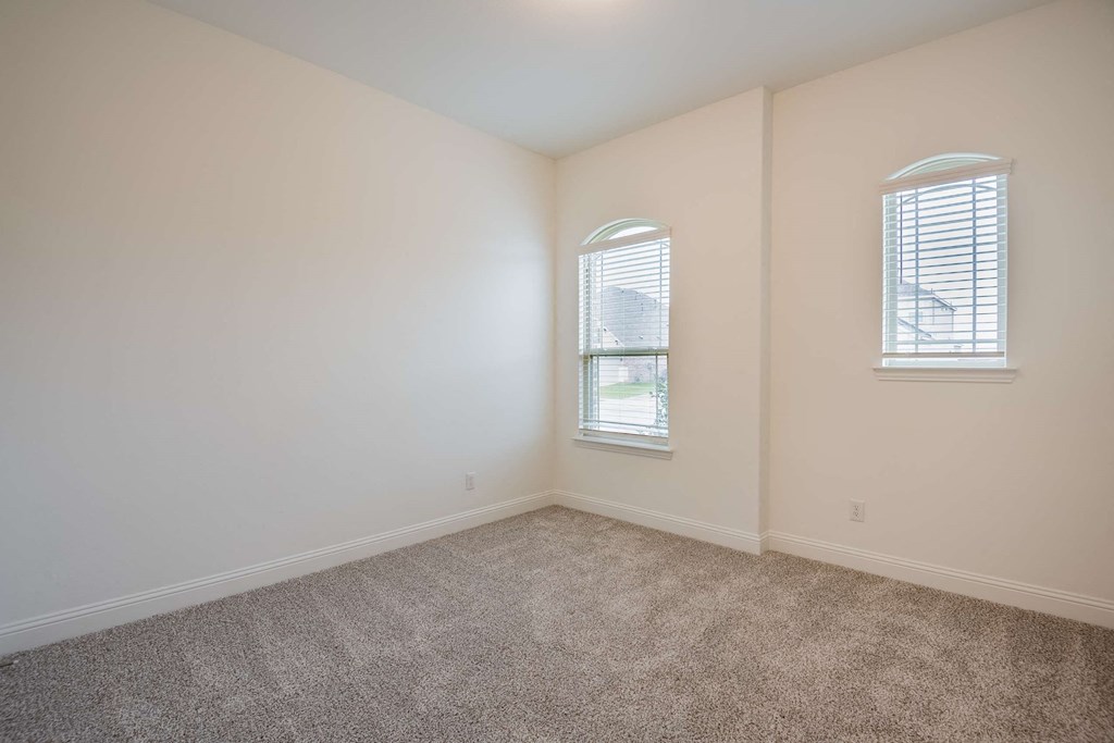 a bedroom with carpet and two windows