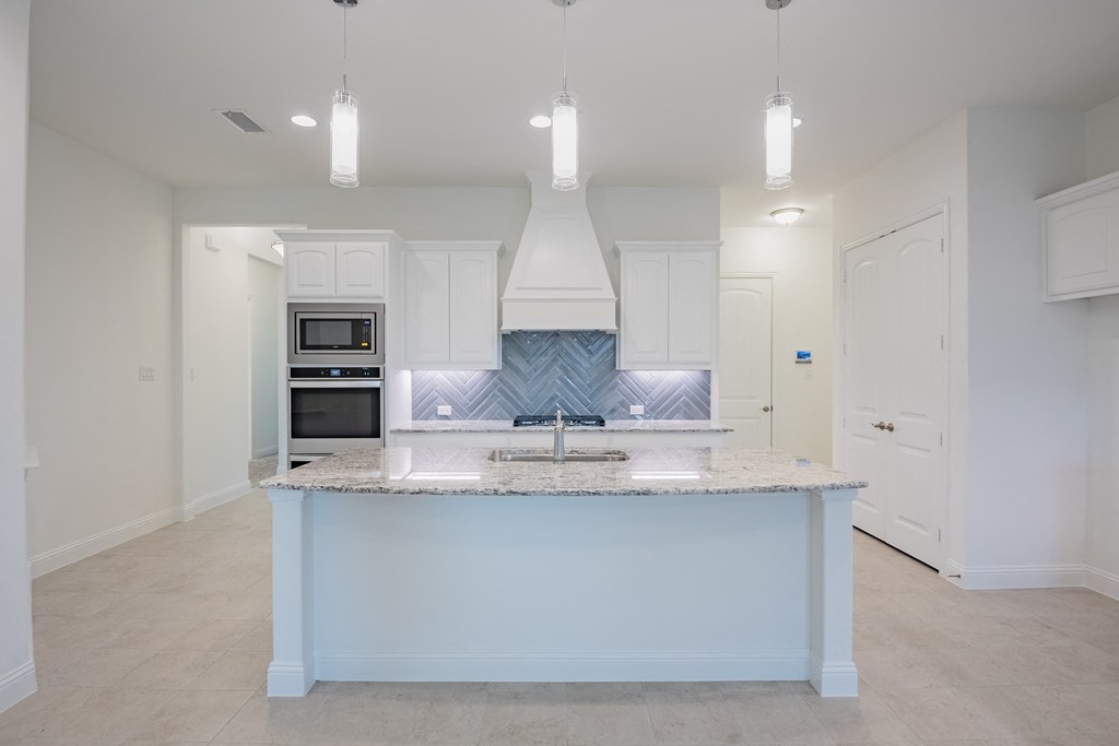 a kitchen with white cabinets and a marble counter top