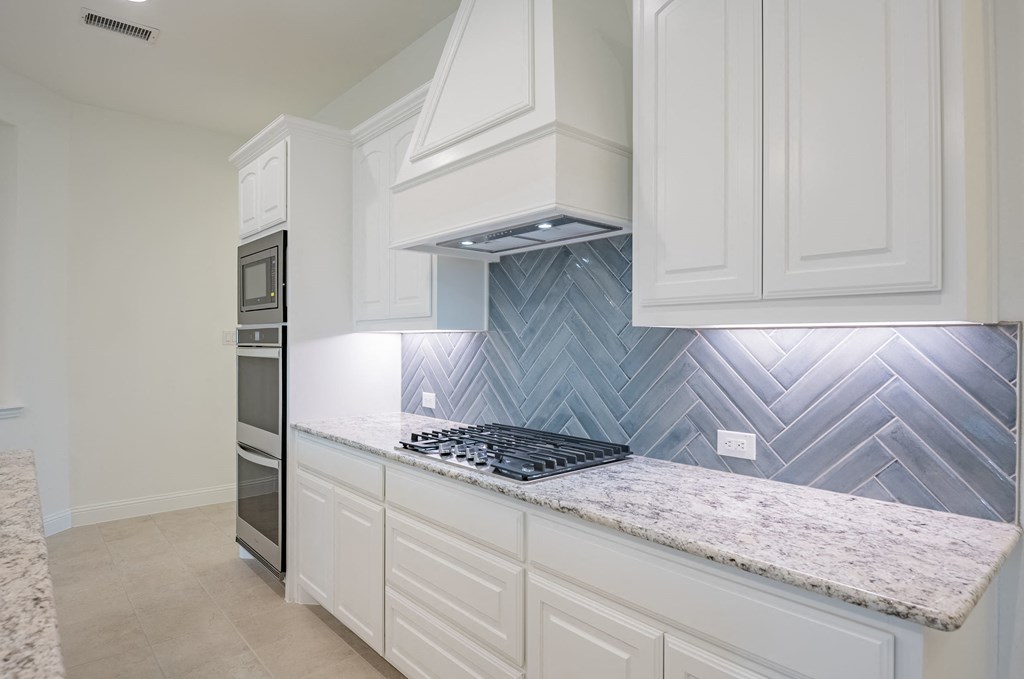 a kitchen with white cabinets and a marble counter top
