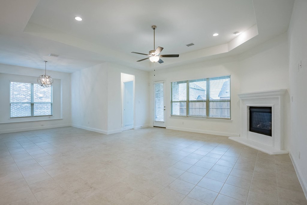 an empty living room with a fireplace and a ceiling fan