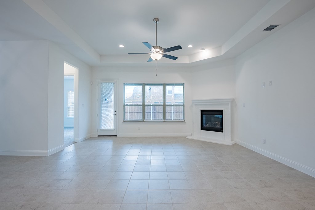 an empty living room with a fireplace and a ceiling fan