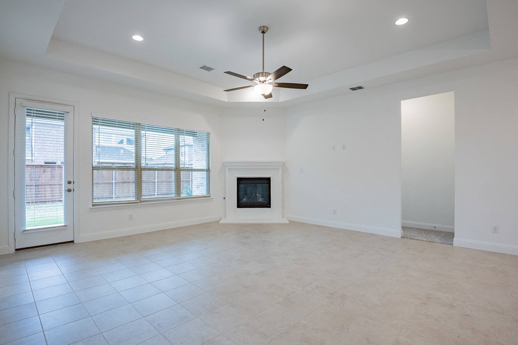 an empty living room with a fireplace and a ceiling fan