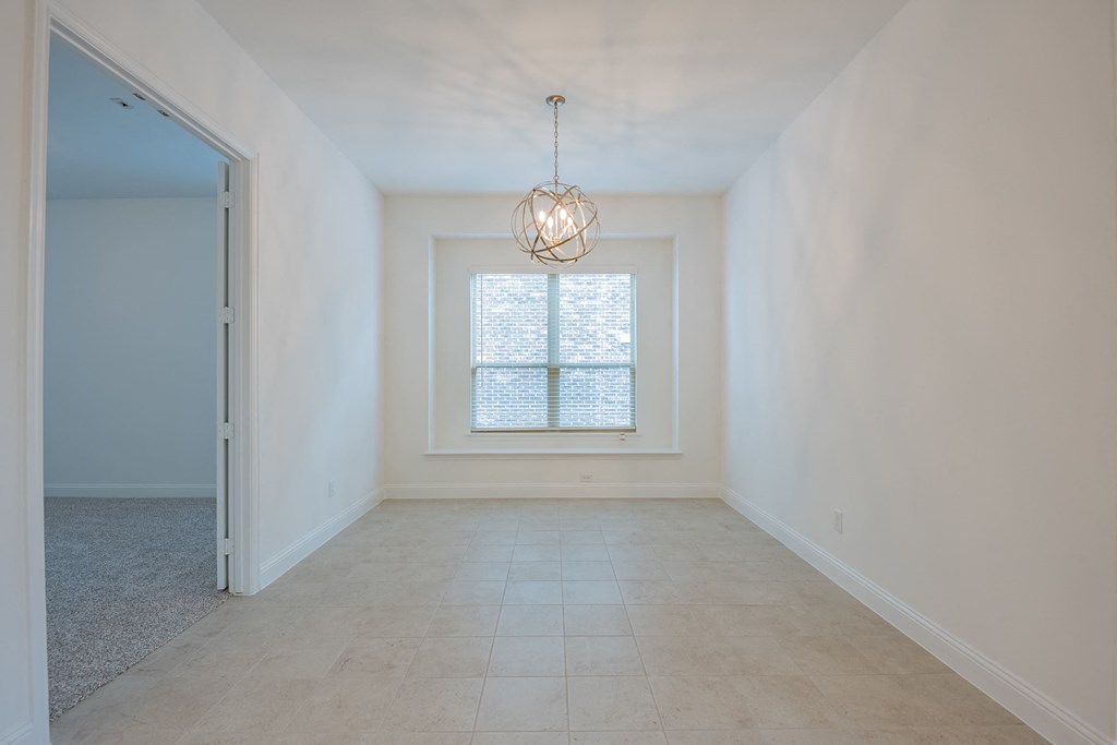 an empty dining room with a window and a chandelier