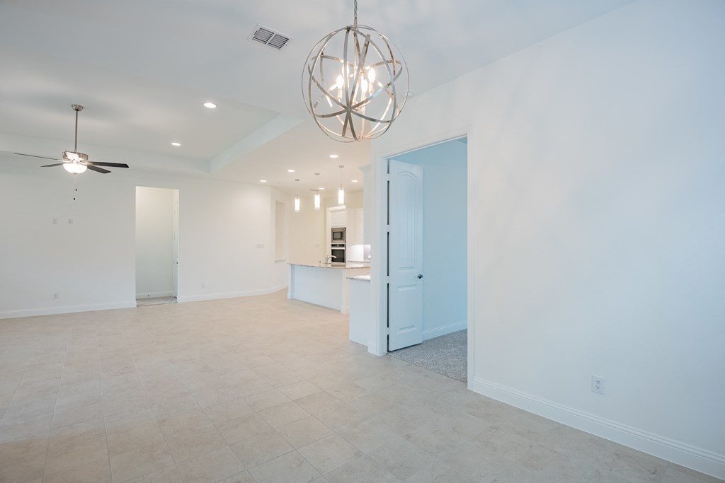 a large living room with white walls and a ceiling fan