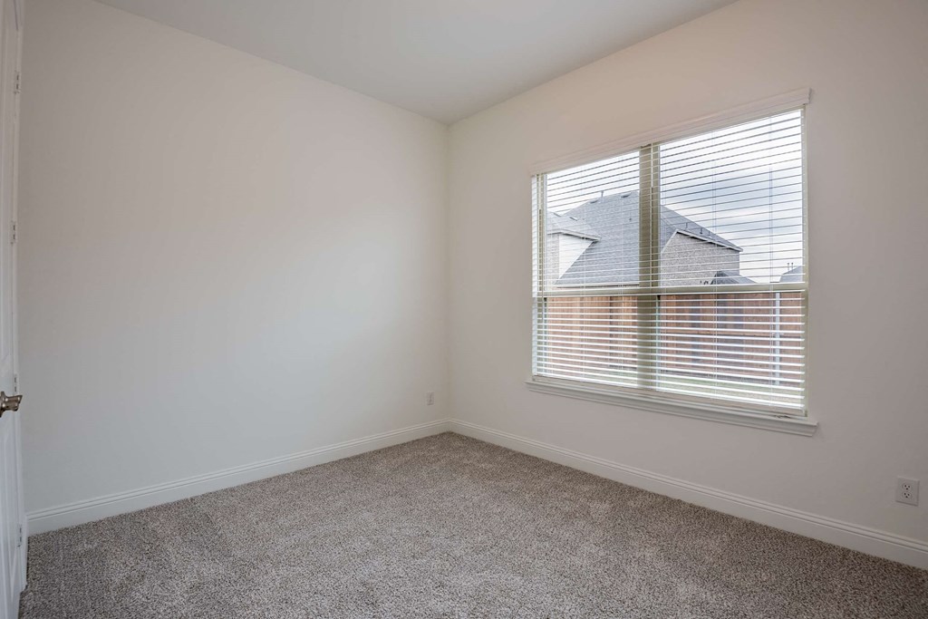 a bedroom with a large window and a carpeted floor