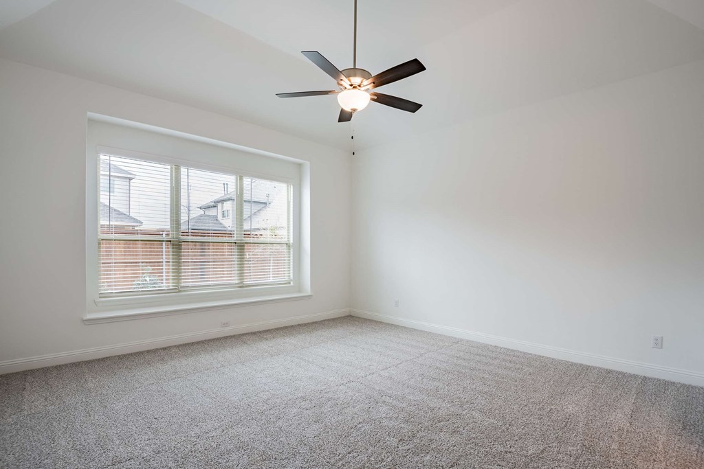 a bedroom with a large window and a ceiling fan