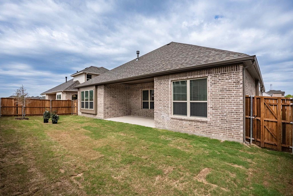a backyard with a brick house and a wooden fence