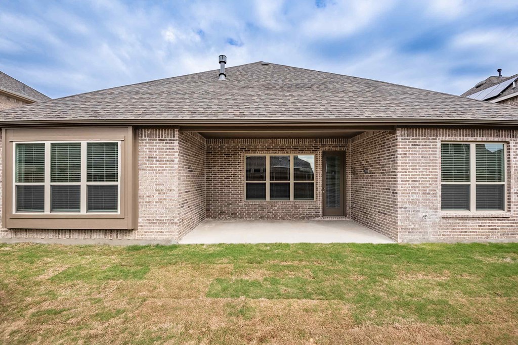 the front of a brick house with a porch and a lawn
