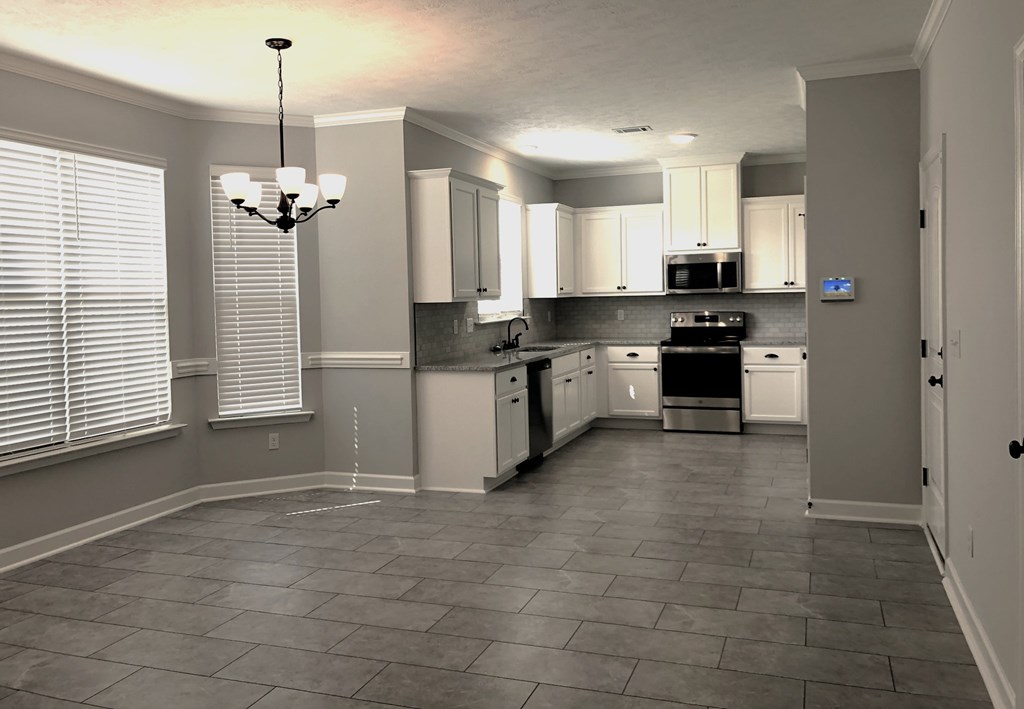 A kitchen with a tile floor and a chandelier hanging from the ceiling.