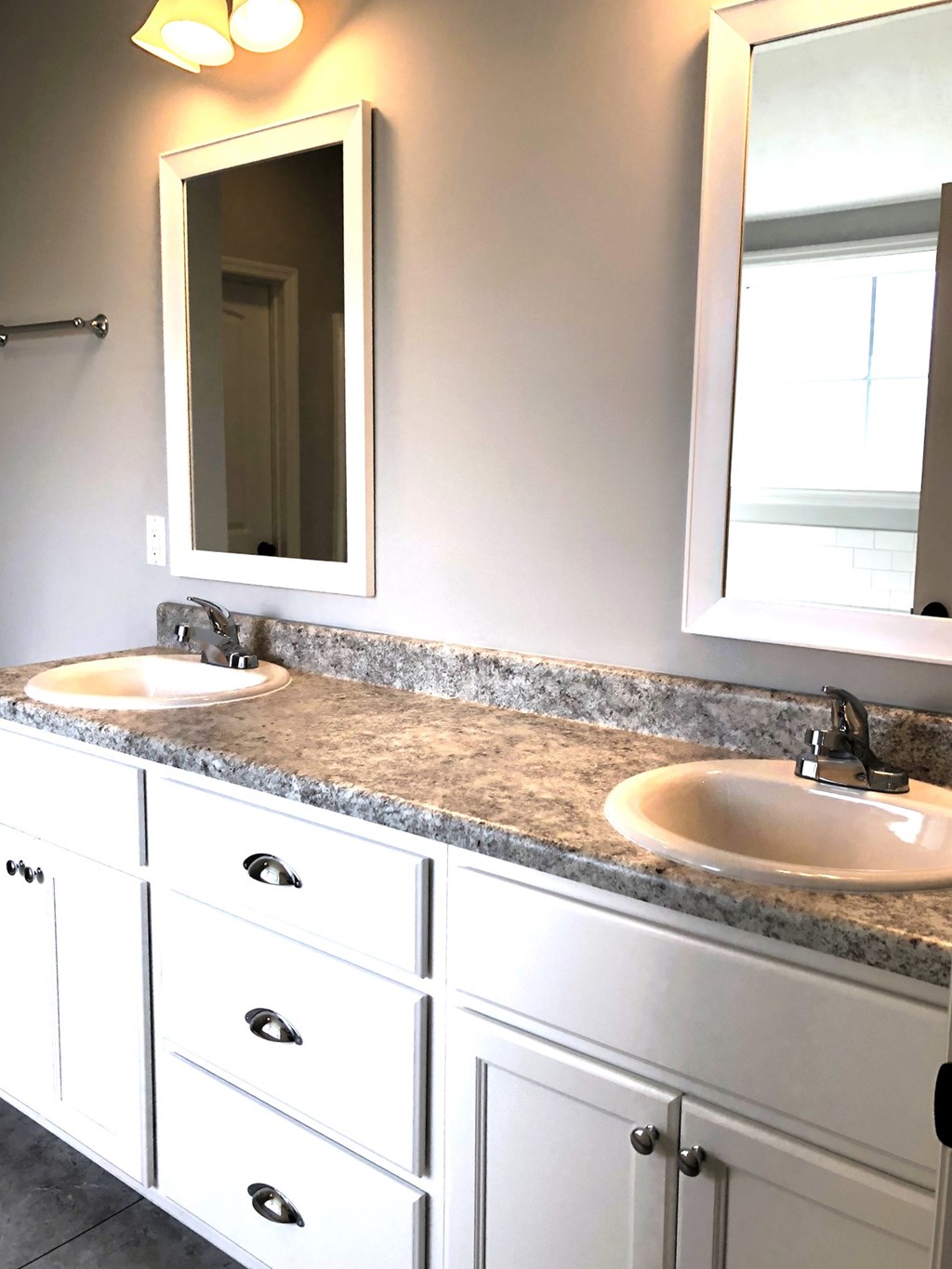 A bathroom with a granite countertop and two sinks.