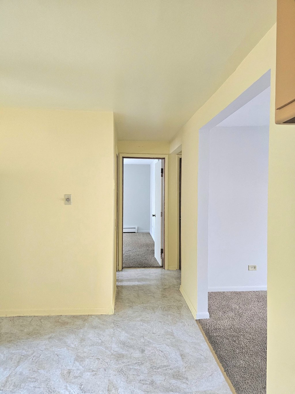 an empty room with a hallway and a door to a bedroom