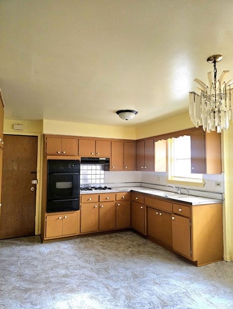an empty kitchen with wooden cabinets and a chandelier