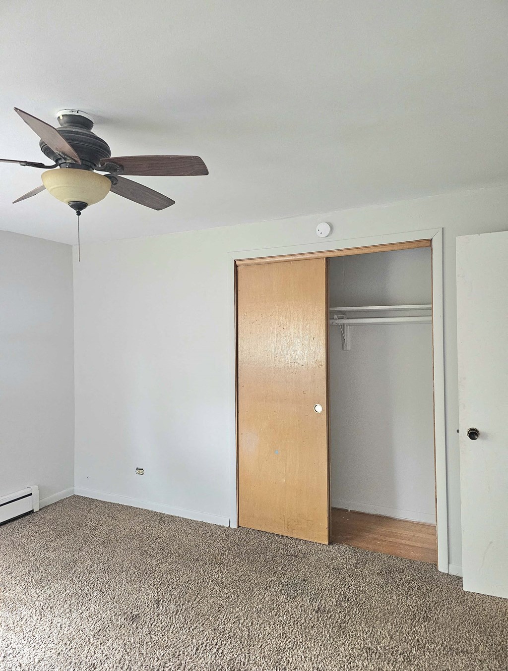an empty room with a ceiling fan and a closet