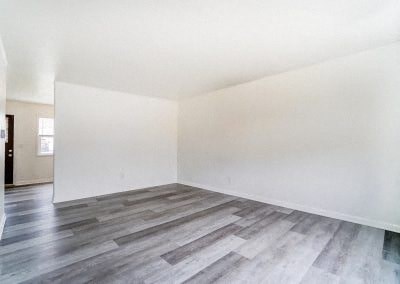 an empty room with white walls and wood floors