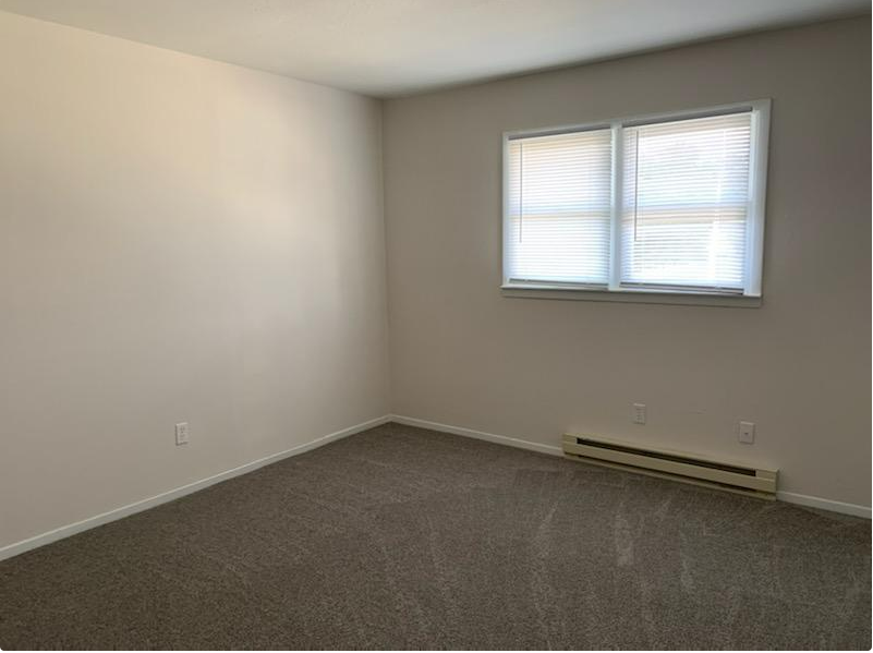 an empty room with a window and a carpet
