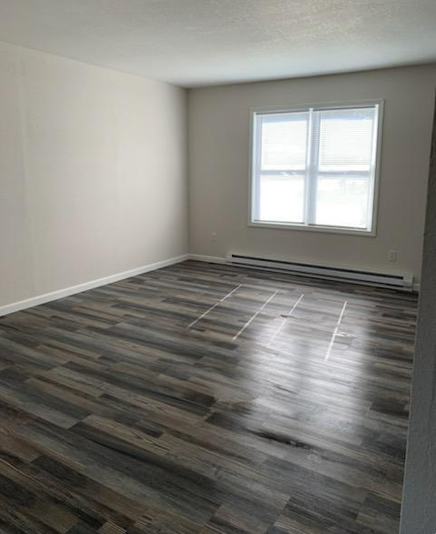 a empty room with a window and wooden floors