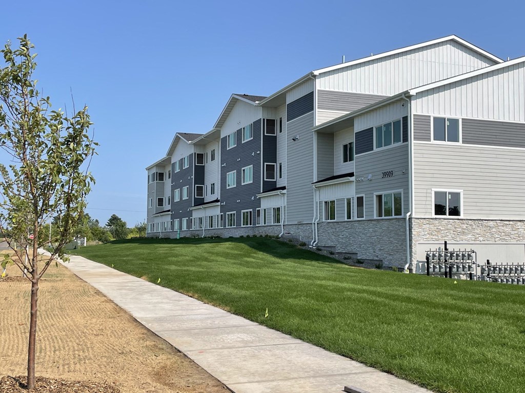 an apartment building with green grass and a sidewalk