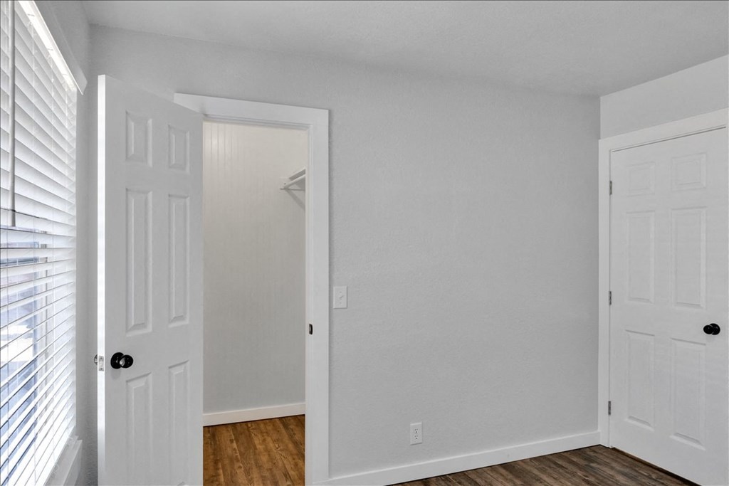 an empty bedroom with white doors and a closet