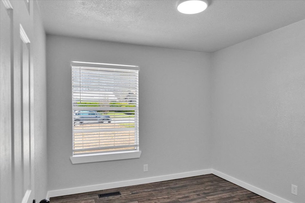 the spacious living room with a large window and wood flooring
