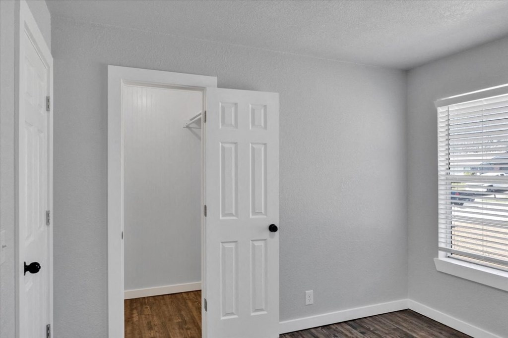 an empty bedroom with a white door and a window